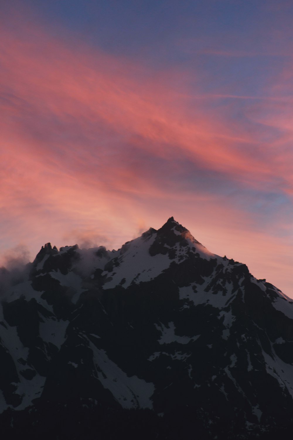 a snow covered mountain under a pink sky