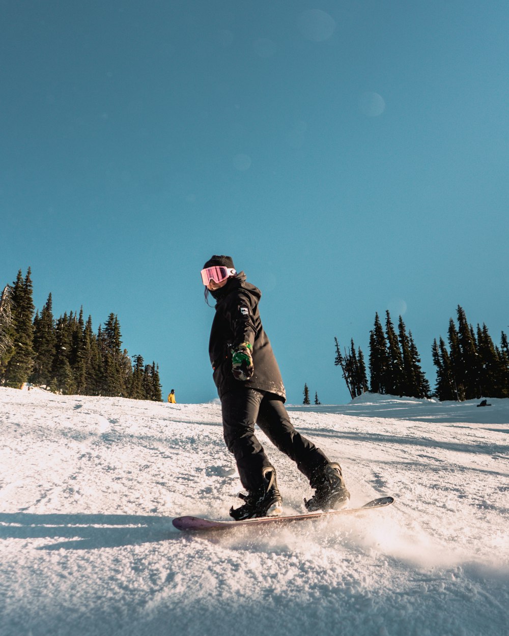 a person riding a snowboard down a snow covered slope