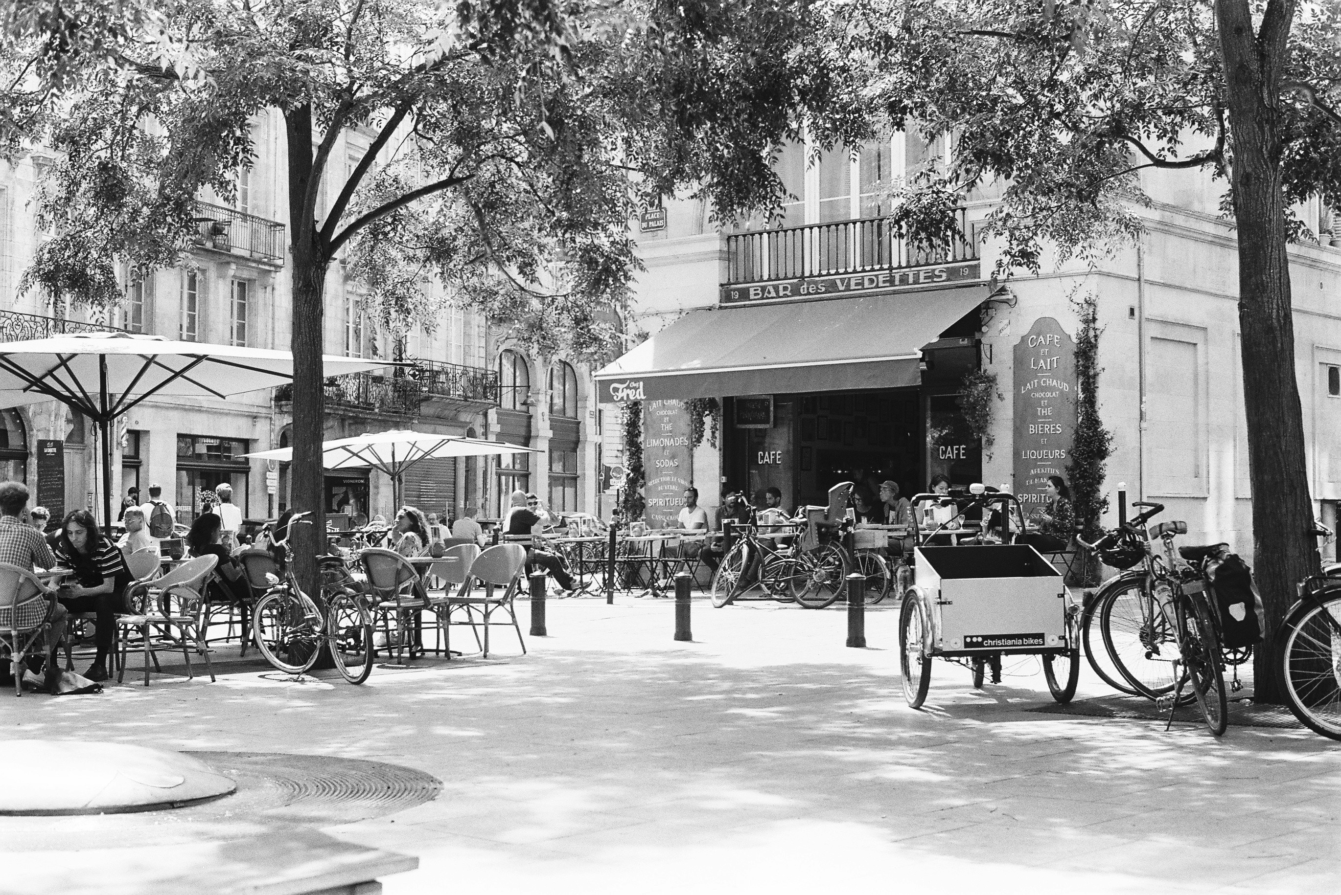 a black and white photo of people sitting at tables in front of a building