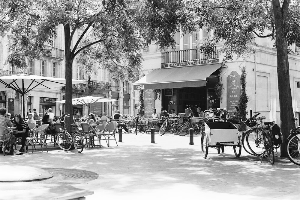 a black and white photo of people sitting at tables in front of a building