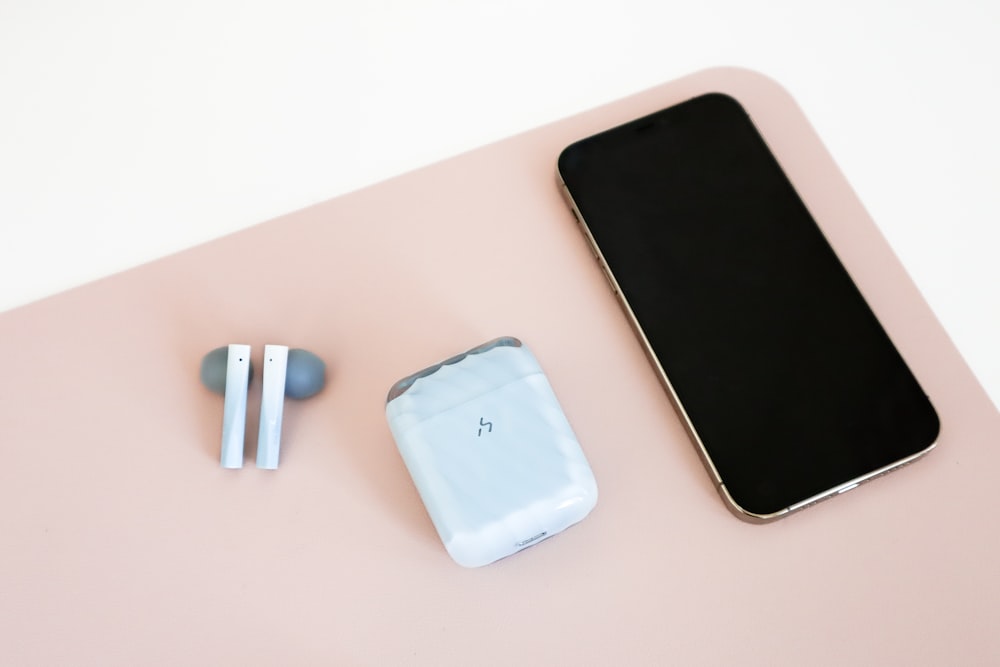 a cell phone, ear buds, and a charger on a table