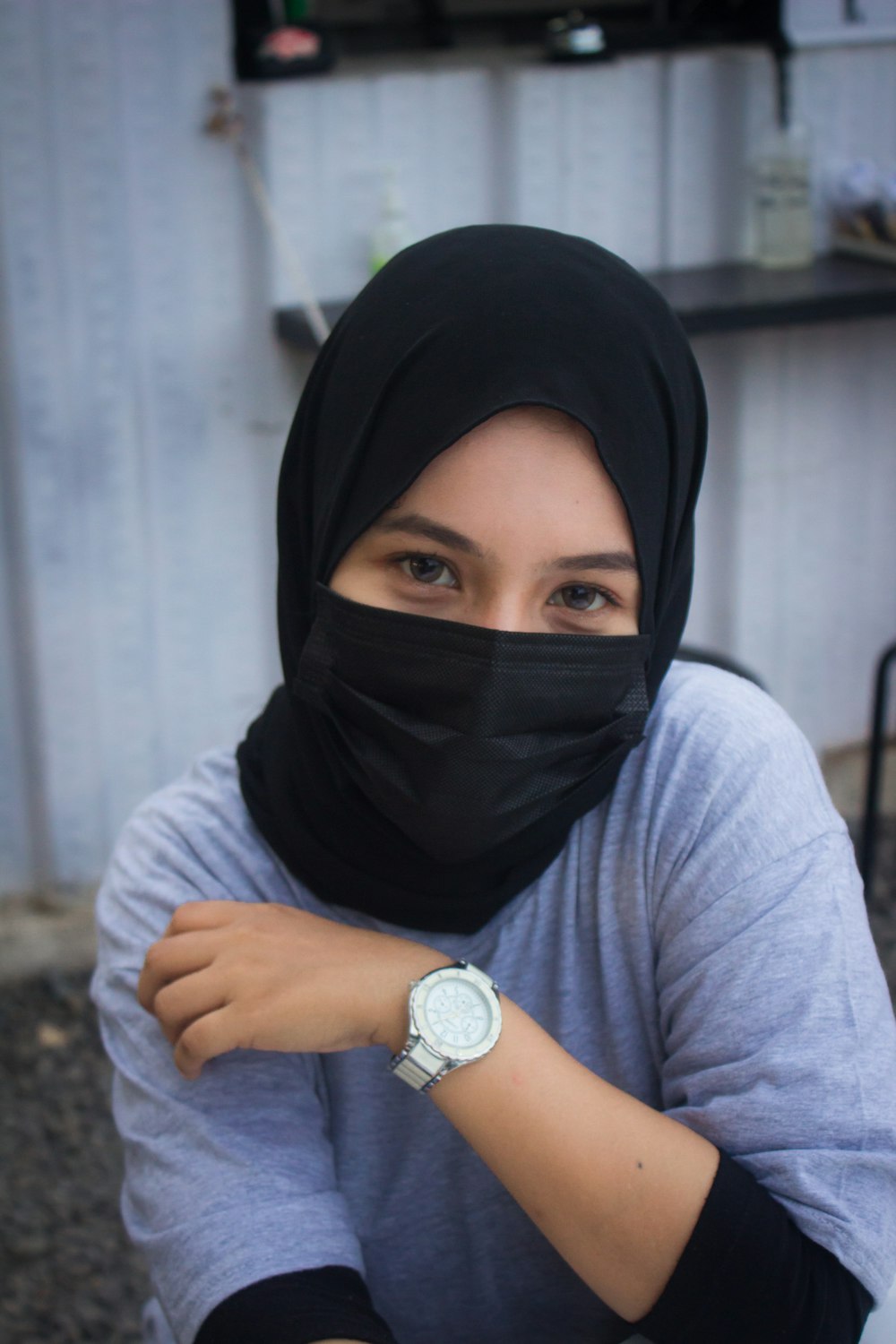 a woman wearing a black mask and a watch