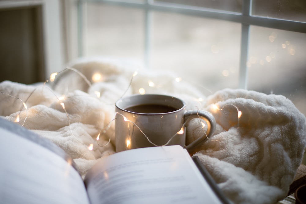 una taza de café y un libro sobre una manta