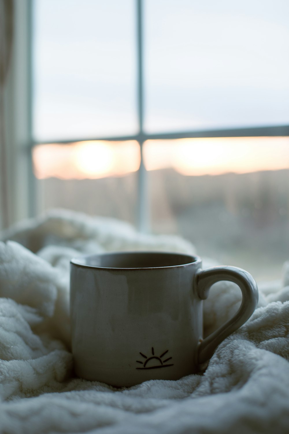 a coffee cup sitting on top of a white blanket