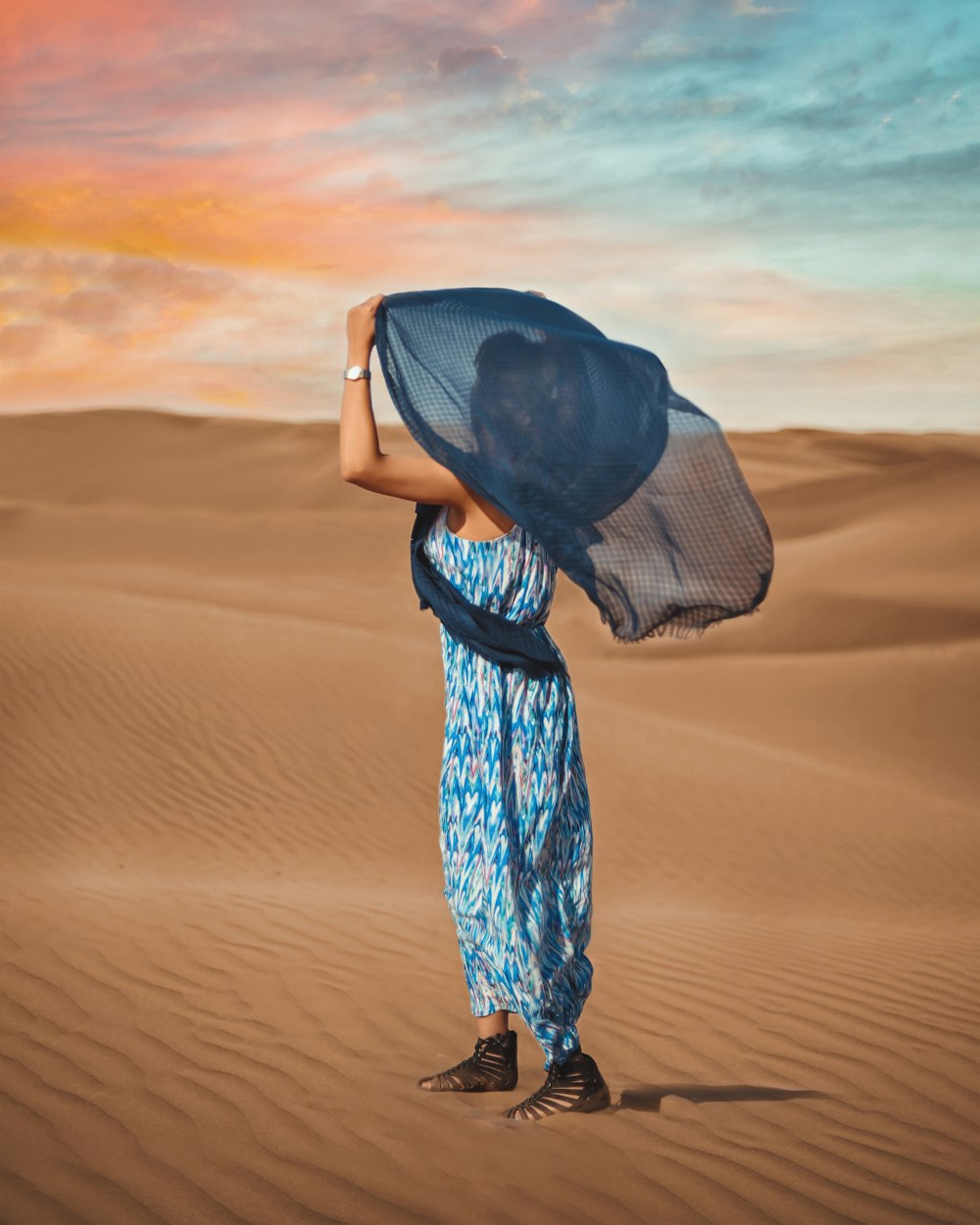 Une femme en robe bleue tenant un foulard bleu sur la tête