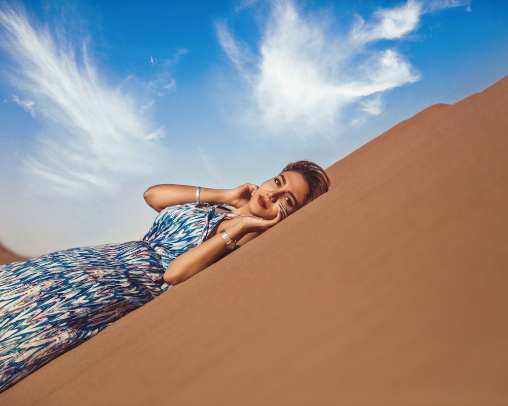 a woman laying on a sand dune in the desert