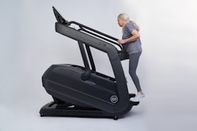 An elderly woman smiling while doing light stretching exercises in a bright, welcoming gym