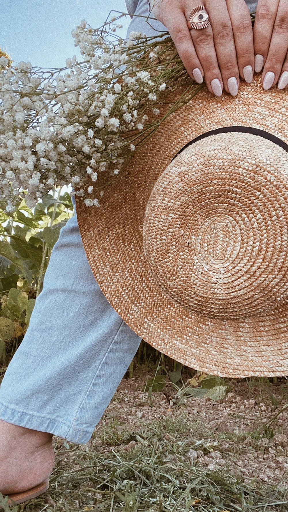 uma mulher que segura um chapéu de palha em um campo