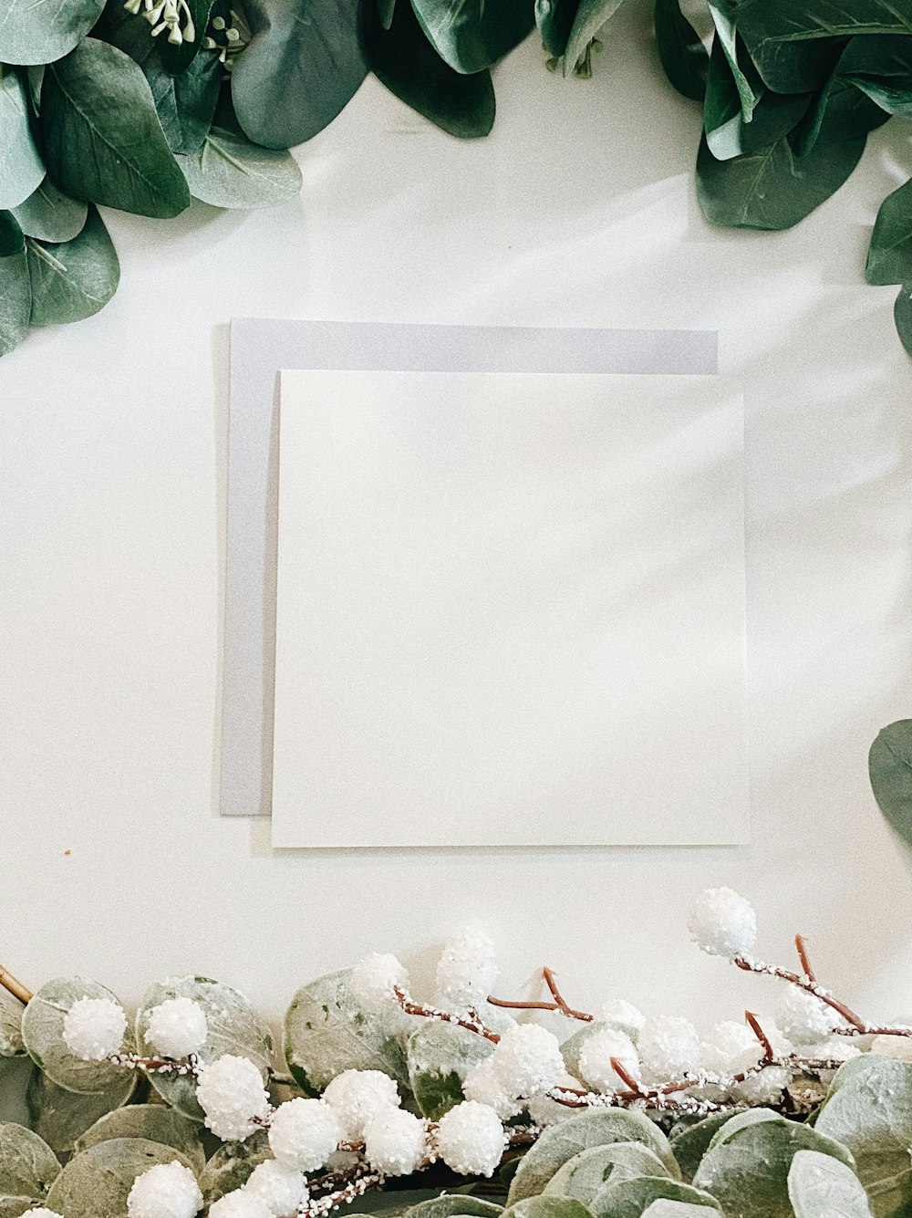 a white card surrounded by greenery and white flowers