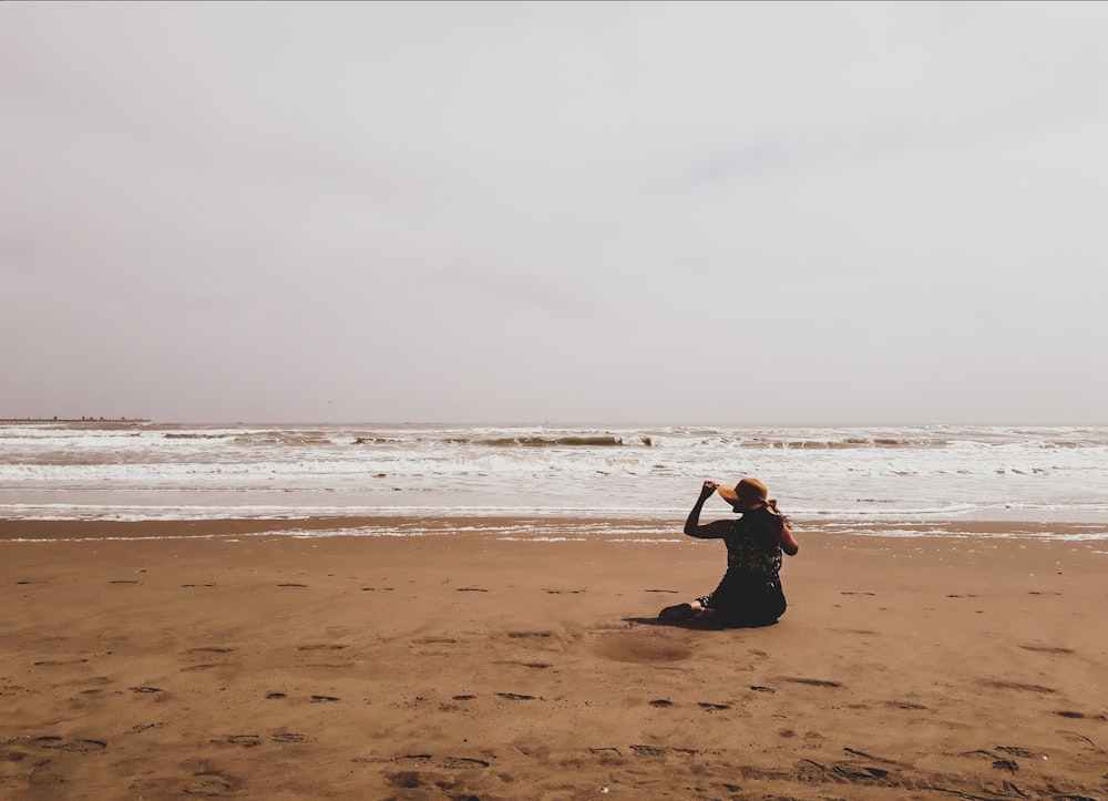a woman sitting on a beach looking at the ocean