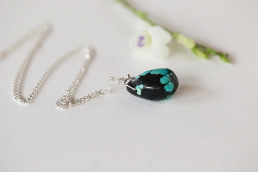Elegant silver necklace with a turquoise stone displayed on a soft linen cloth.