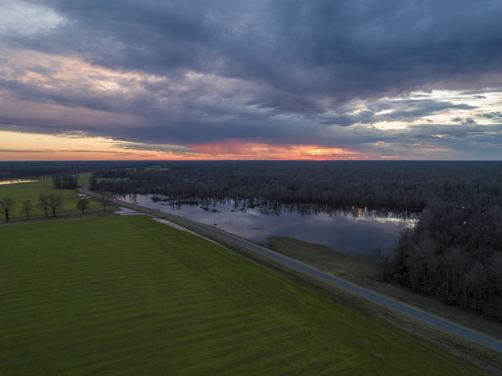 an aerial view of a field and a lake at sunset