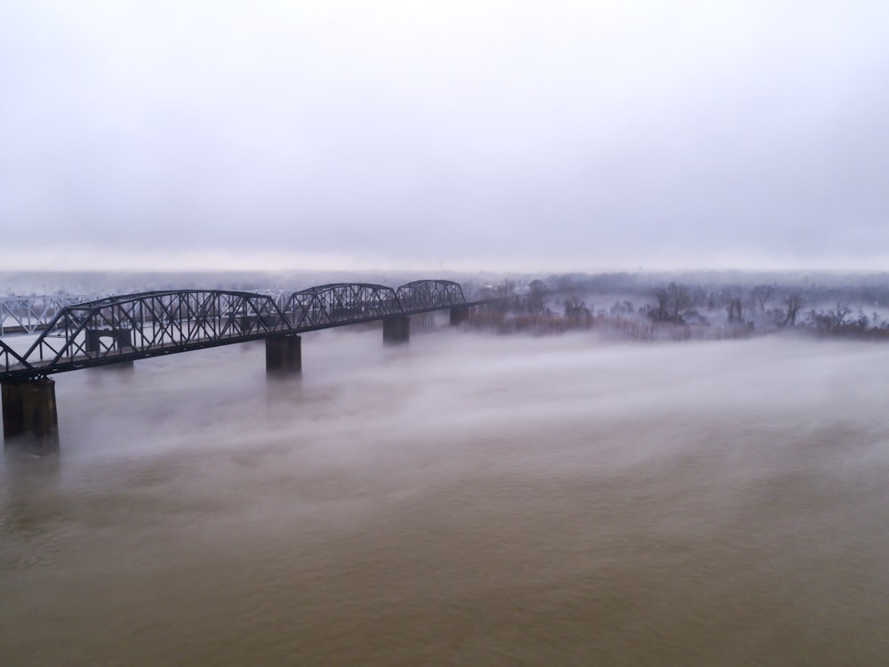 uma ponte sobre um corpo de água em um dia nebuloso