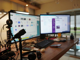 a desk with two monitors and a microphone