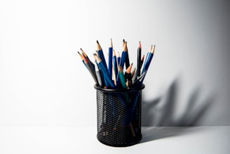 a cup filled with pencils sitting on top of a table