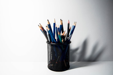 a cup filled with pencils sitting on top of a table