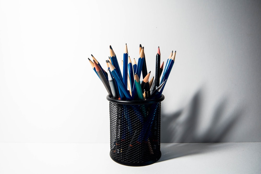 a cup filled with pencils sitting on top of a table