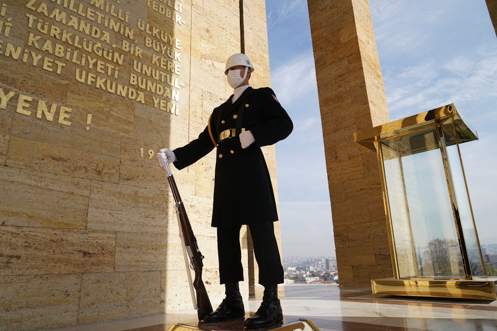 a statue of a man in uniform standing next to a wall