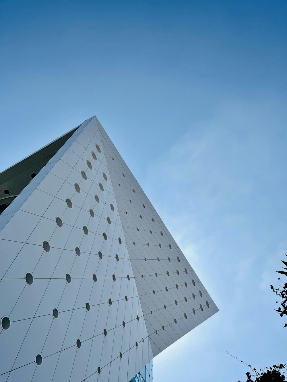 a tall white building sitting next to a tree