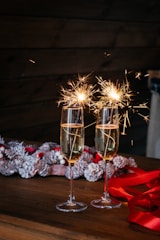 two glasses of champagne with sparklers on a table