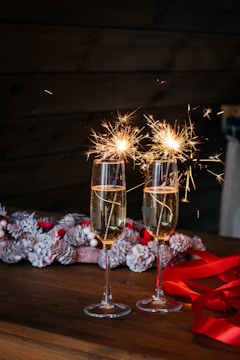 two glasses of champagne with sparklers on a table