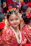 A smiling young girl twirling in a pastel pink lehenga choli with gold accents at a festive family gathering.