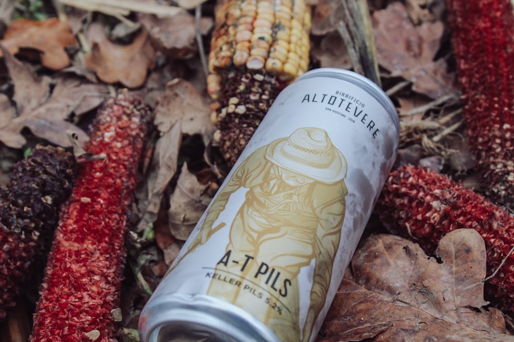 a can of beer sitting on top of a pile of leaves