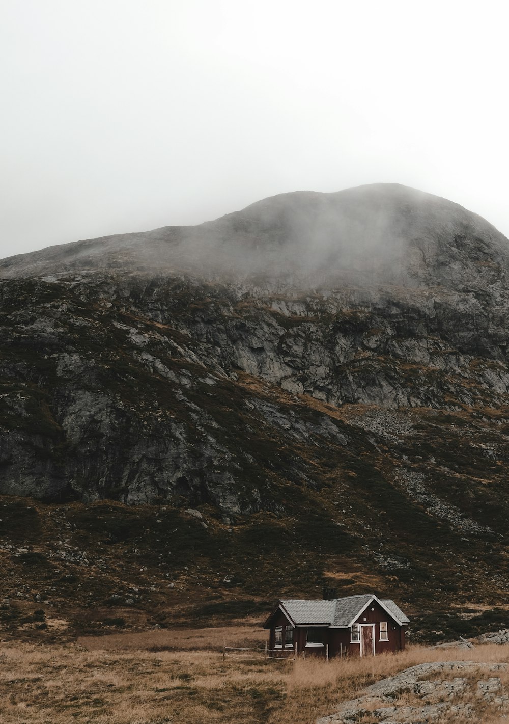 Una casa en medio de un campo con una montaña al fondo