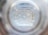 The image captures the view from the bottom inside a clear plastic bottle. The pattern of the bottle’s base features multiple ridges radiating outward from the center, which is a small circular indentation. The plastic is slightly reflective, giving off a translucent, almost glass-like appearance.