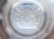 The image captures the view from the bottom inside a clear plastic bottle. The pattern of the bottle’s base features multiple ridges radiating outward from the center, which is a small circular indentation. The plastic is slightly reflective, giving off a translucent, almost glass-like appearance.