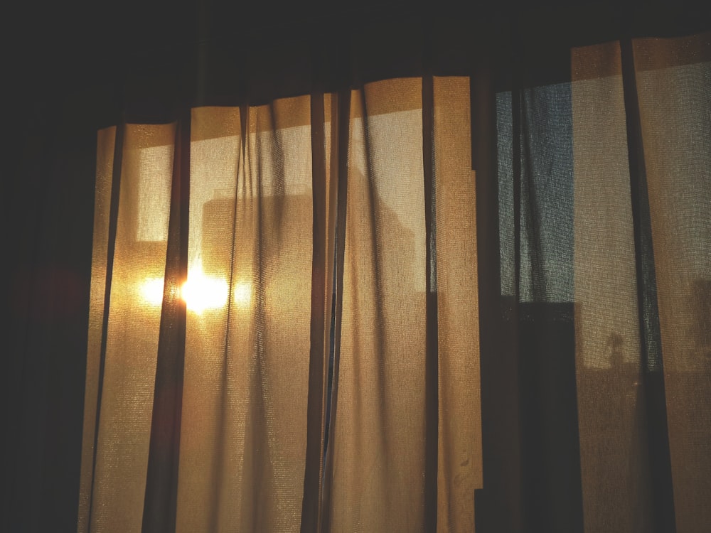 the sun is shining through the curtains of a window