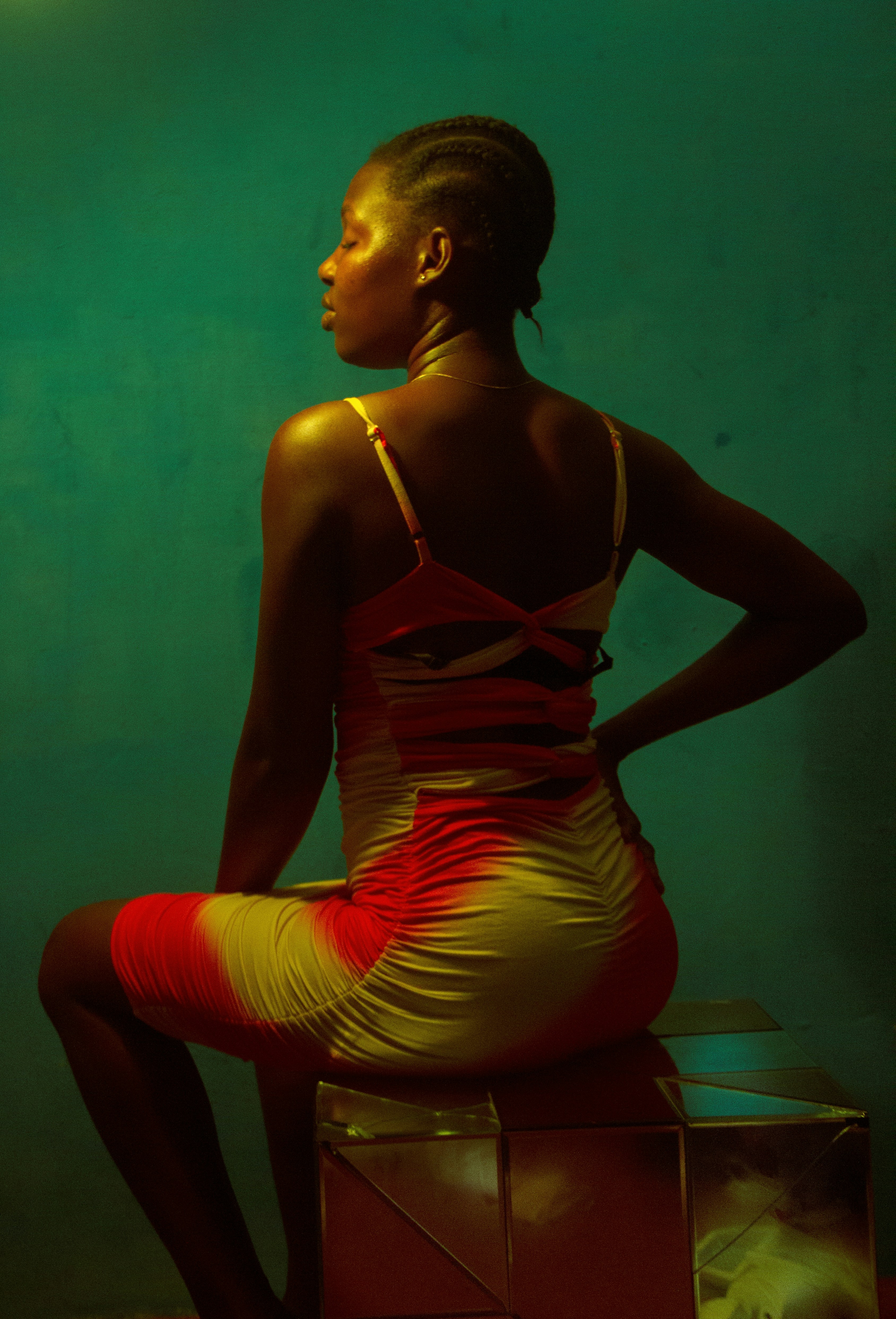 a woman in a red and yellow dress sitting on a box