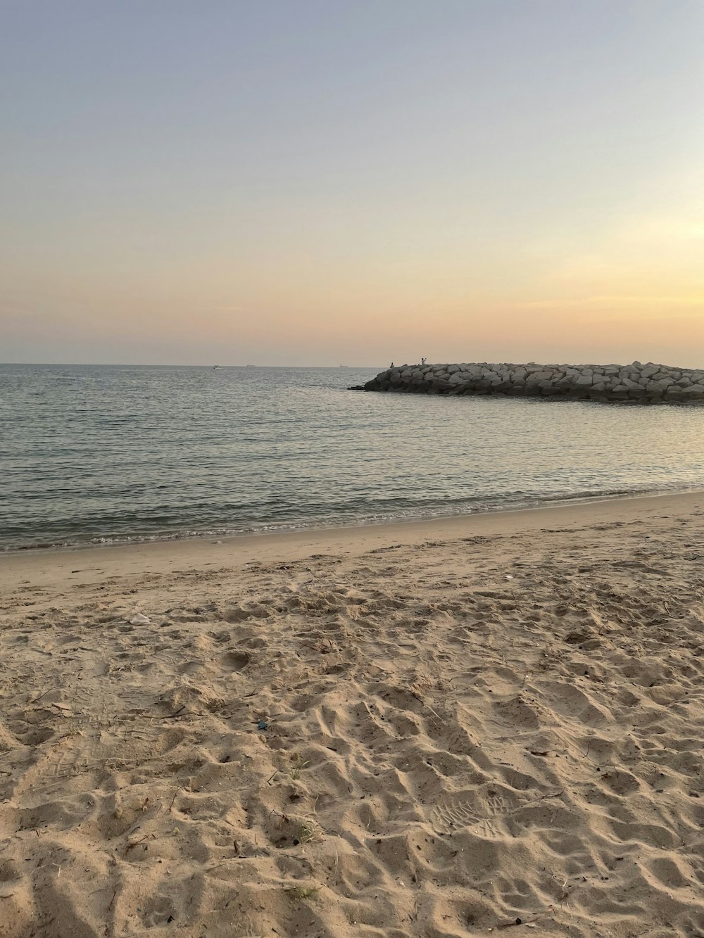 a sandy beach with a body of water in the background