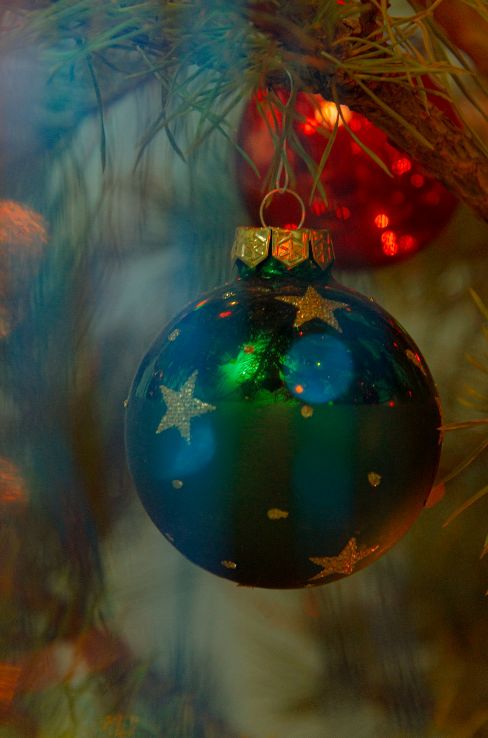 a blue ornament hanging from a christmas tree