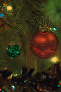 Laser engraved Christmas ornaments hanging on a festive tree branch.