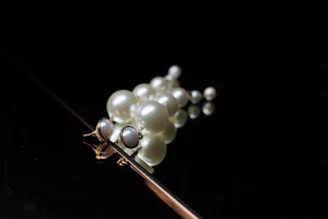 A cluster of lustrous pearls with subtle off-white tones, arranged delicately on a dark charcoal background.
