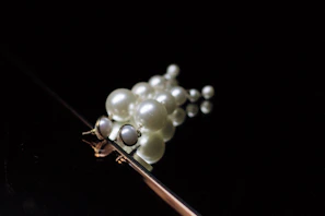 A cluster of lustrous pearls with subtle off-white tones, arranged delicately on a dark charcoal background.