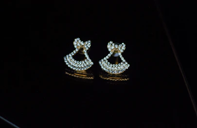 Elegant pair of 1 gram gold earrings resting on a velvet surface, showcasing fine craftsmanship