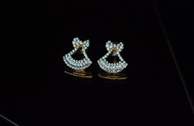 A pair of lightweight gold plated earrings displayed on a black velvet cushion.