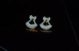 A pair of sparkling diamond earrings displayed against a black velvet background