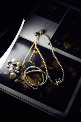 Elegant pearl earrings catching the light beside a vintage book.