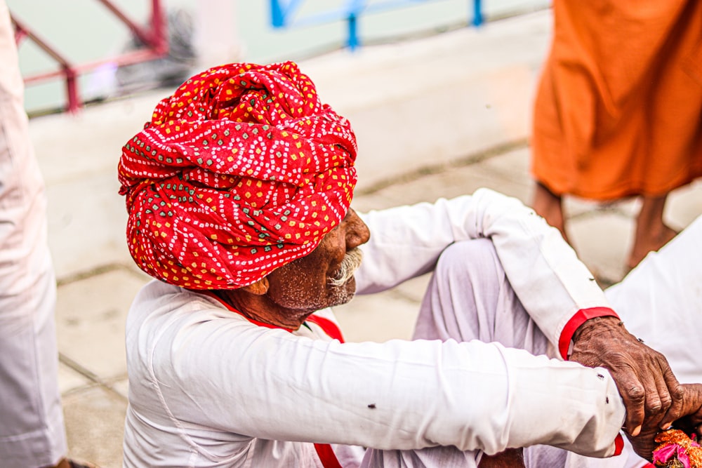 Un hombre con un turbante rojo sentado en el suelo