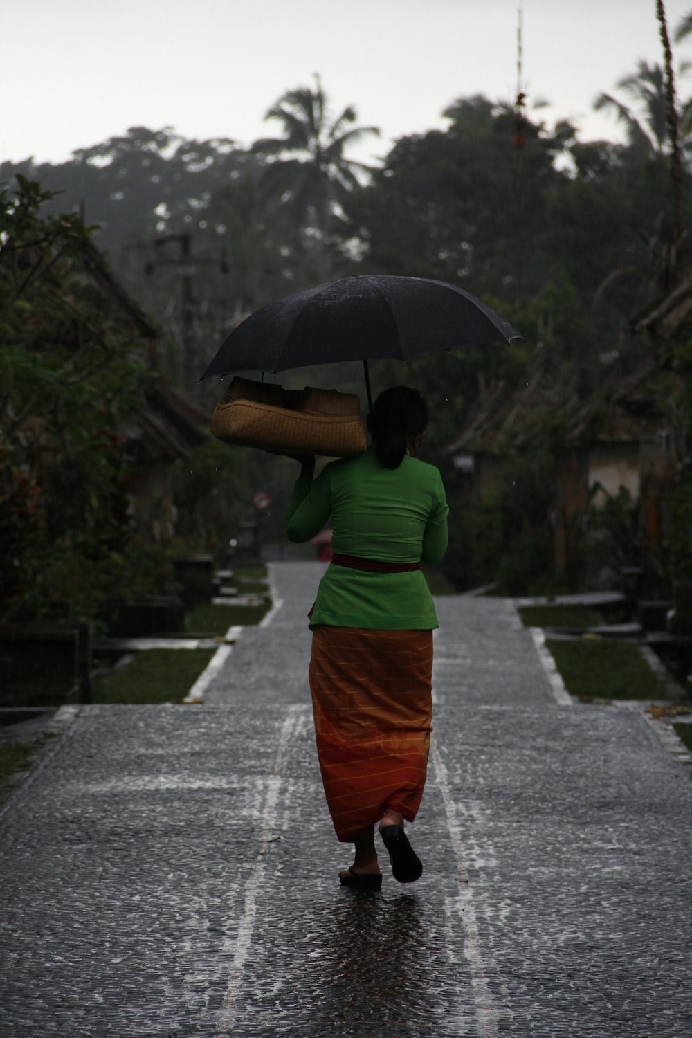 Eine Frau geht mit einem Regenschirm eine Straße entlang