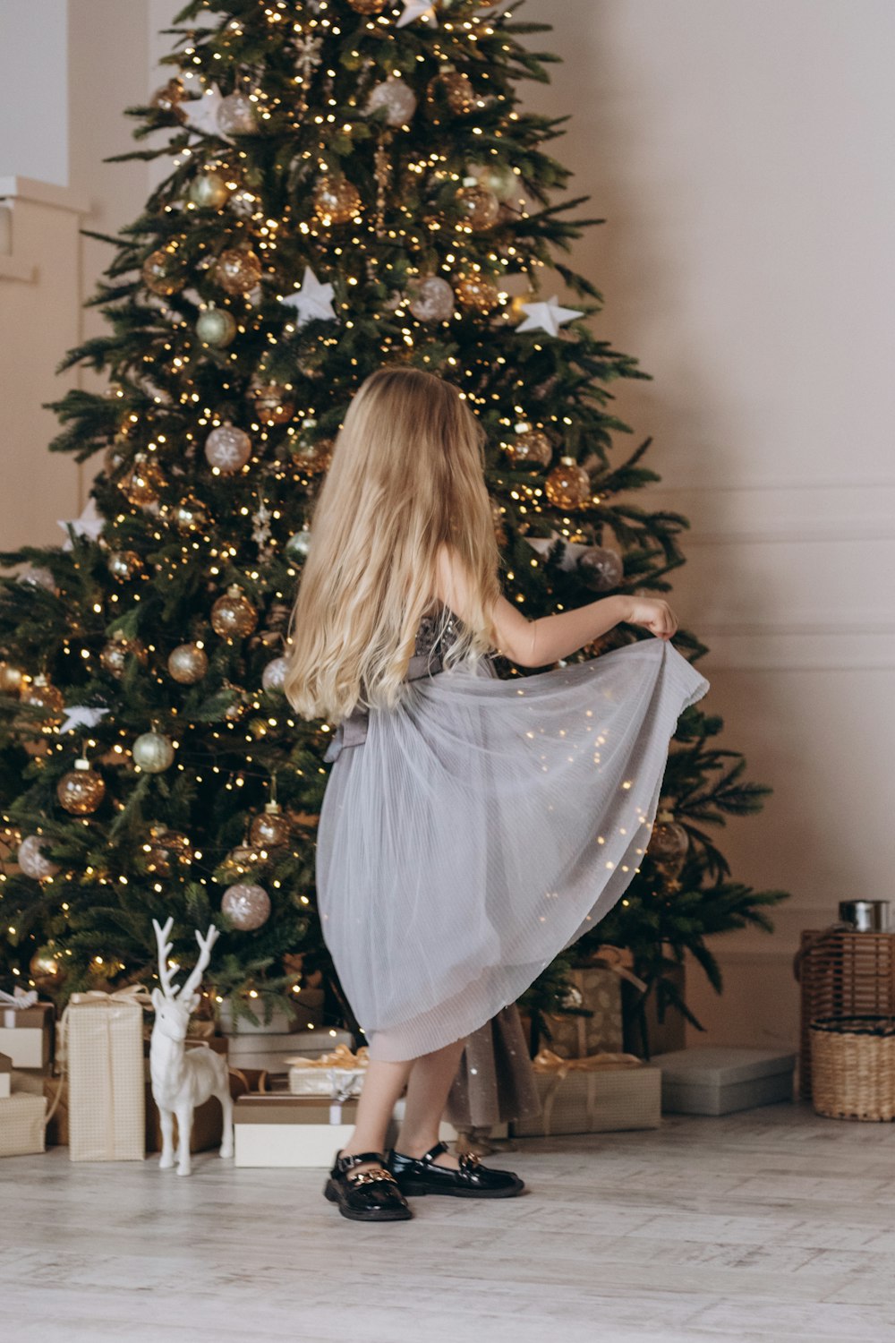 a little girl standing in front of a christmas tree