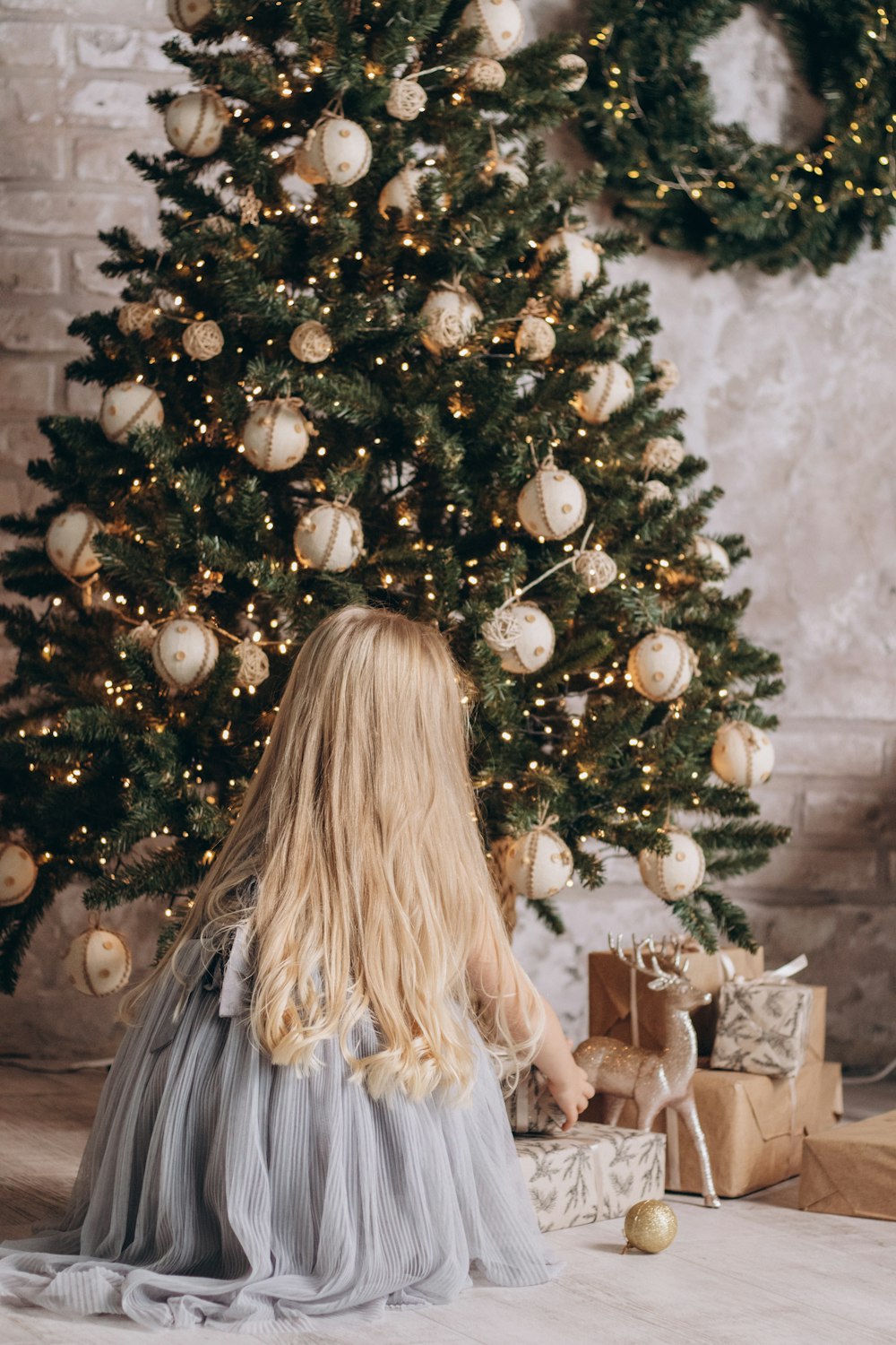 a little girl sitting in front of a christmas tree
