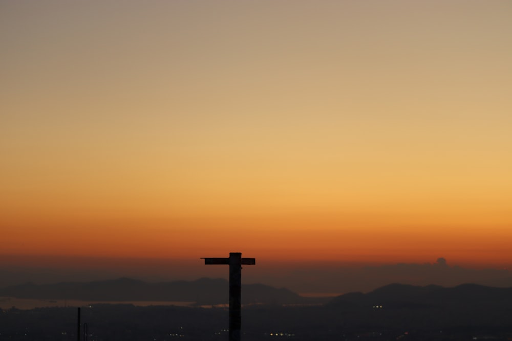 a cross on top of a hill at sunset