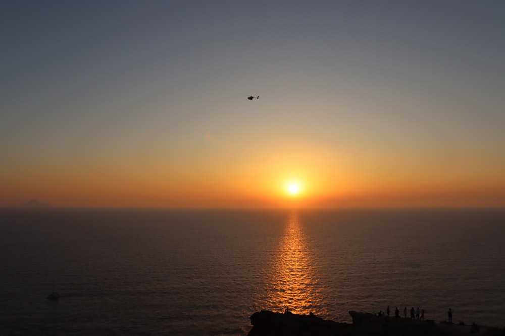 the sun is setting over the ocean with a boat in the distance