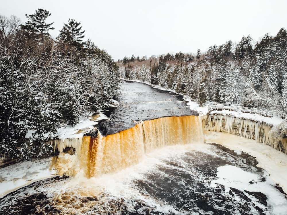 a waterfall in the middle of a snowy forest