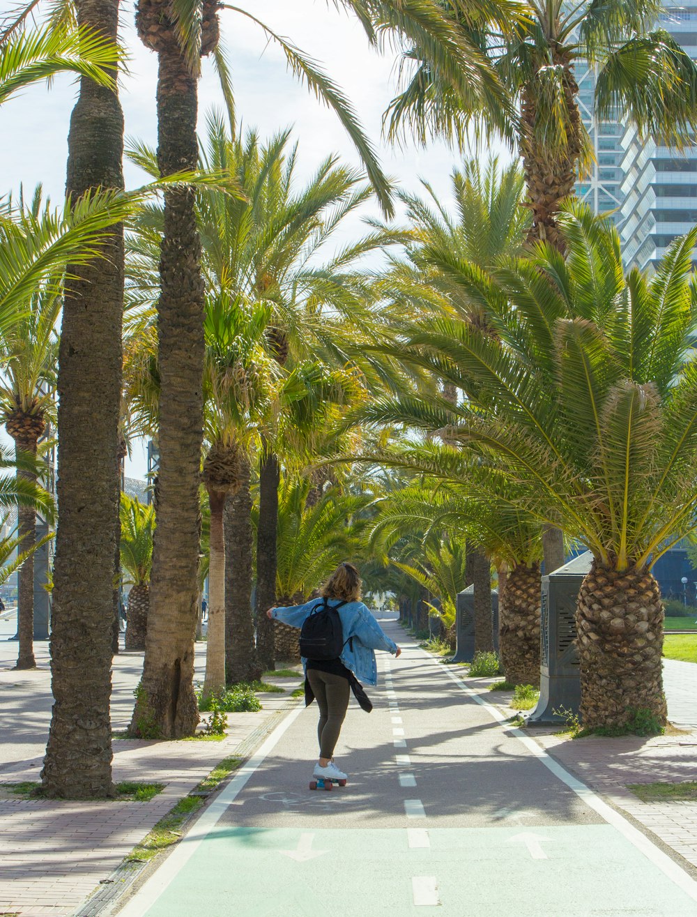 a man riding a skateboard down a street next to palm trees