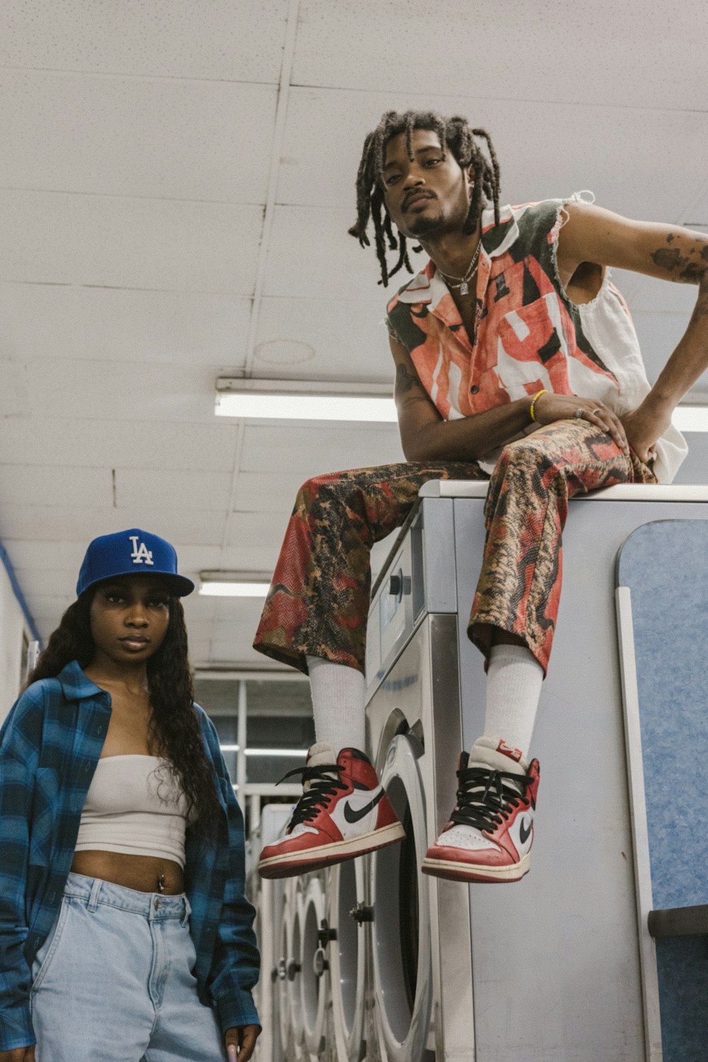 a man sitting on top of a washing machine next to a woman